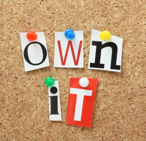 The phrase Own It in magazine letters on a cork notice board